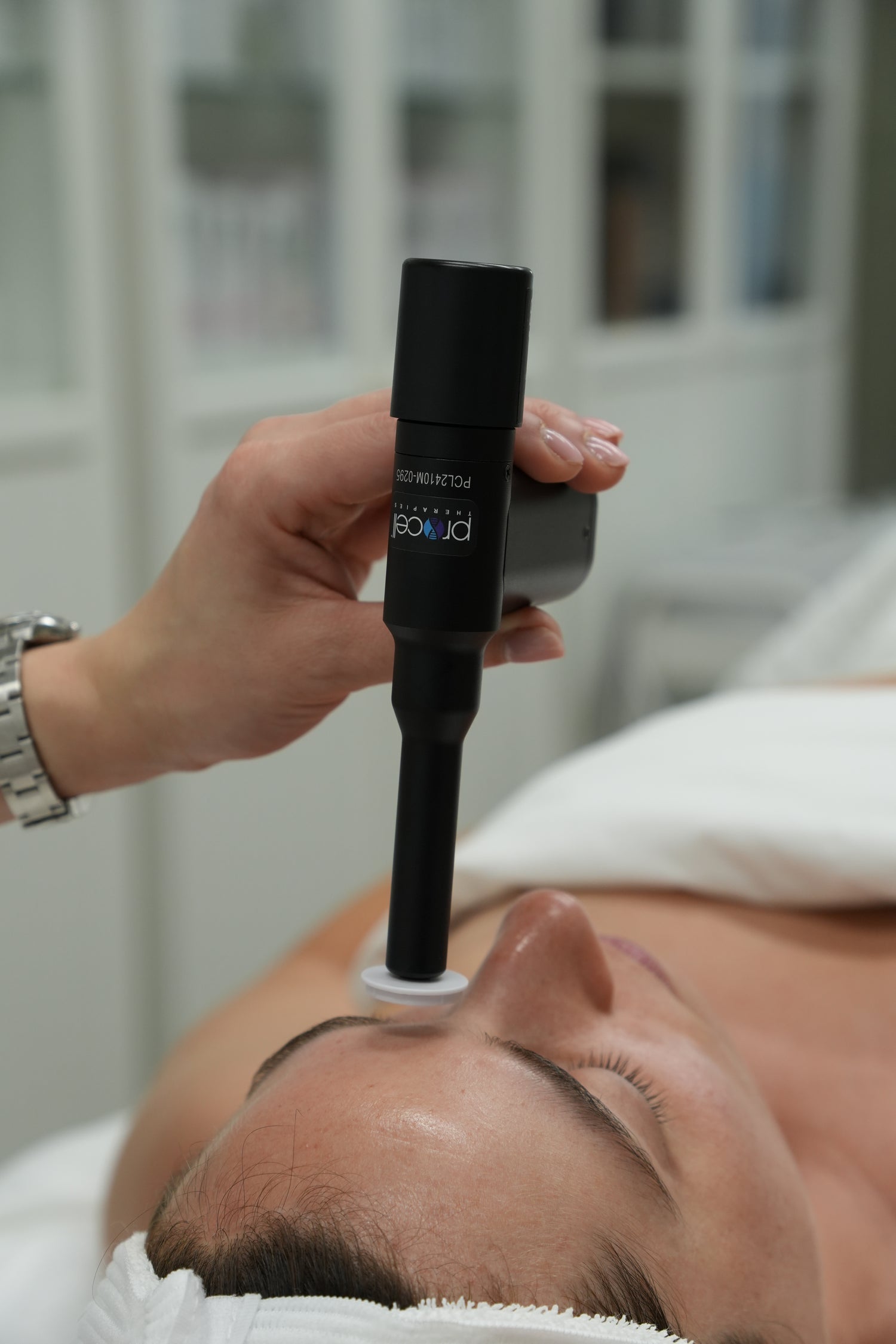 Person receiving a facial treatment with a Procell Microchanneling device held by a hand.